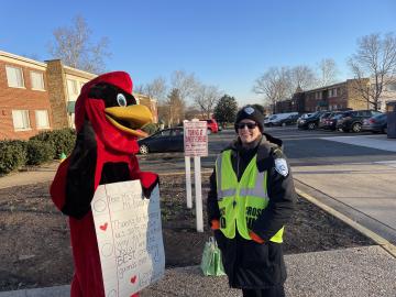 Abingdon Cardinal standing with Abingdon's crossing guard with a poster thanking her for keeping children safe