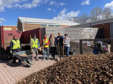 Company and PTA staff posing behind a pile of donated woodchips